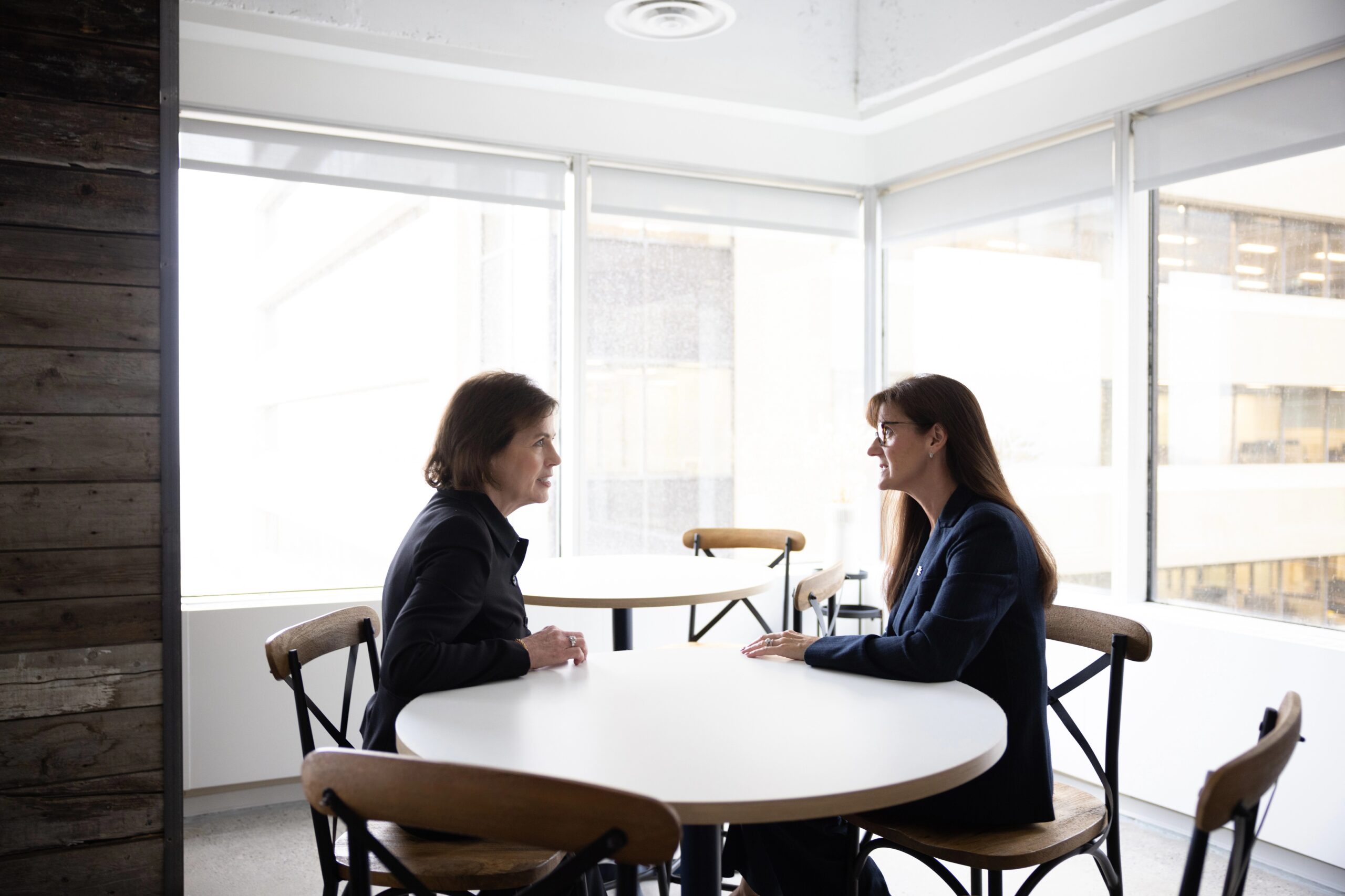 Two Bright Wire Leadership coaches seated at a table in a modern office, discussing global leadership development solutions.